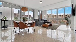 Un salon spacieux avec un coin repas, de grandes fenêtres et une vue sur la ville.