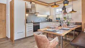 A modern kitchen with white cabinets, a built-in oven, and a dining area with a wooden table set for four.