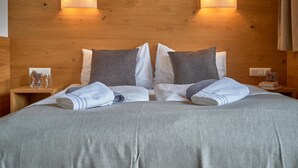 A neatly made bed with a grey bedspread, two pillows, and a small bedside table with a glass of water and a book.