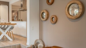 Ein modernes Wohnzimmer mit Ledersofa, einem Essbereich mit Holztisch und Stühlen sowie einer Küche im Hintergrund.