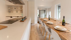 Eine moderne Küche mit Kochinsel, integrierten Geräten und einem Essbereich mit Holztisch und Stühlen.