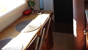Ein Zimmer mit Holzbalkendecke, einem Fenster mit Blick, einer Tür mit rundem Spiegel und einer kleinen Pflanze auf dem Fensterbrett.