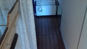 Eine enge Treppe führt zu einem kleinen, abgeschlossenen Raum mit Holzboden und einer weißen Tür.