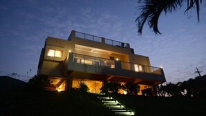 Ein modernes, zweistöckiges Haus mit Balkon, einer zur Eingangstür führenden Treppe und einem hellen Innenraum.