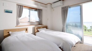 Ein Hotelzimmer mit zwei Betten, einem großen Fenster und Meerblick.