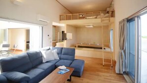 Ein modernes Wohnzimmer mit einem blauen Sofa, einem Holztisch und einem Etagenbett im Hintergrund.