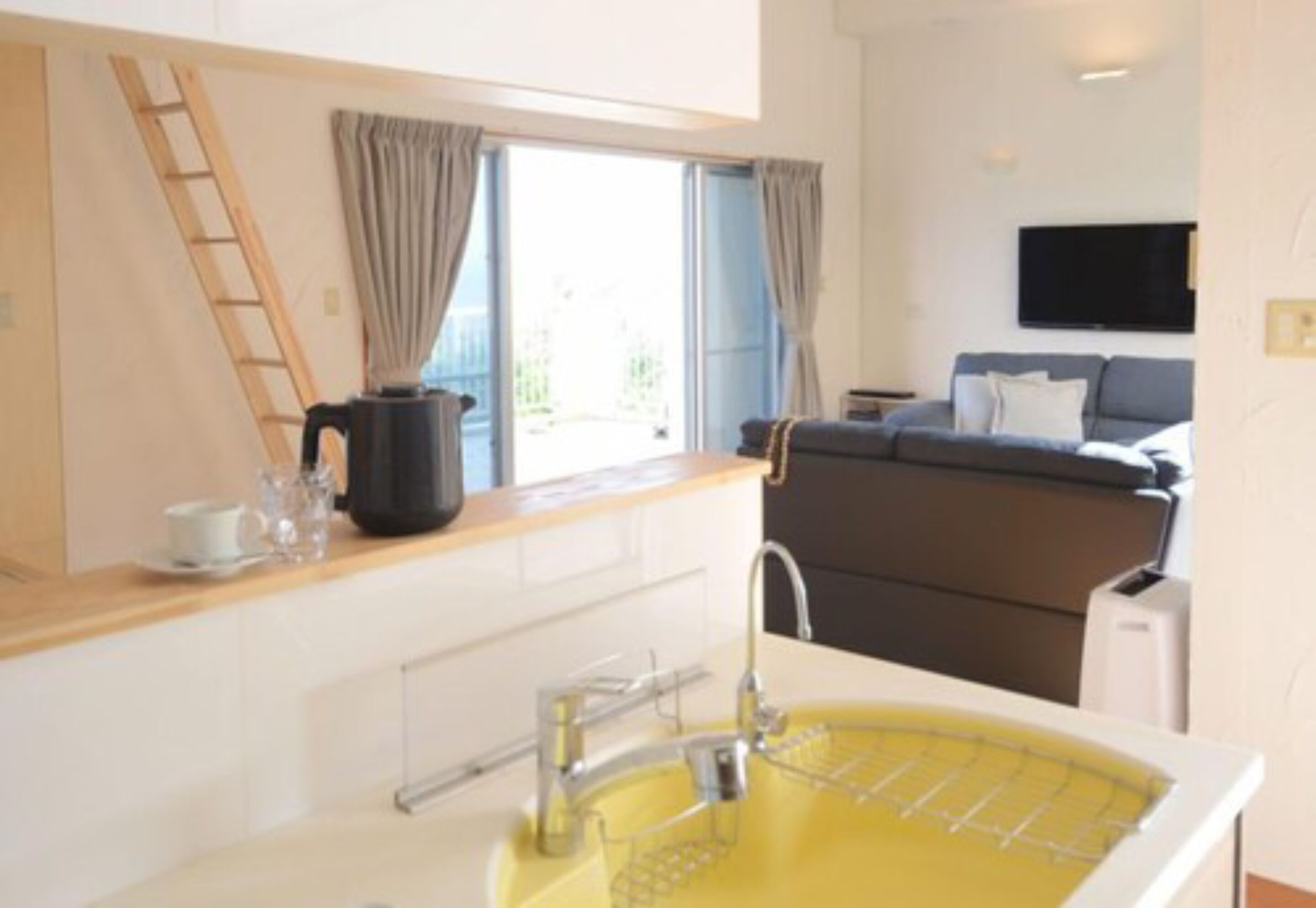 A modern kitchen with a yellow sink, a wooden countertop, and a window with curtains.