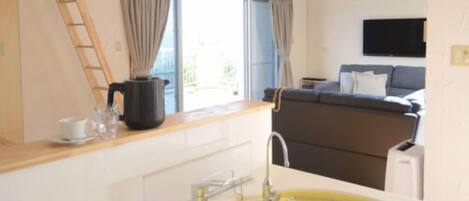 A modern kitchen with a yellow sink, a wooden countertop, and a window with curtains.
