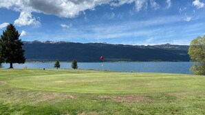 A golf course with a lake and mountains in the background. - Cabin in the Pines - 3 Minutes to the beach, docks or golf! (Cascade)