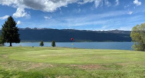 Enjoy a serene golfing experience with a picturesque view of the lake and distant mountains.