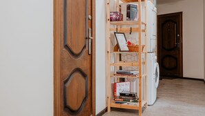Un corridoio con una porta in legno, una libreria con libri e un cesto, e una lavatrice.