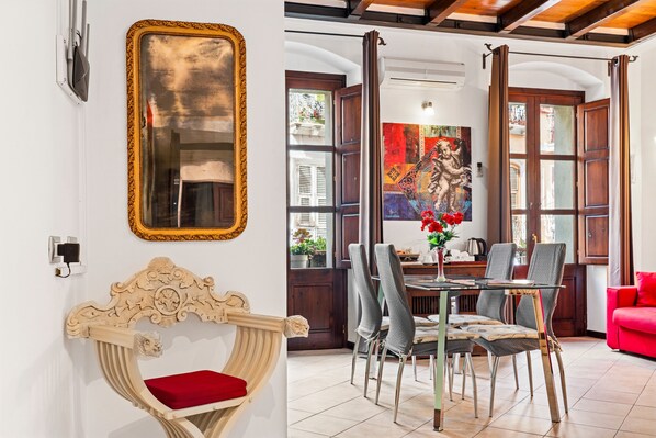 A dining area with a table, chairs, and a red sofa.