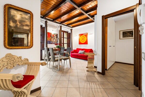 A dining area with a table and chairs, a red sofa, and a wooden ceiling. - Holiday Apartment ‘Sardinia Gem House’ with Sea View, Wi-Fi, A/C & Balcony (Cagliari)