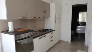 Una cuina moderna amb fogó, rentapesos i armaris.