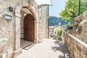 Un bâtiment en pierre avec une porte en bois, un portail en métal et un mur en pierre.