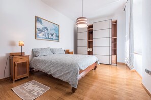Une chambre à coucher comprenant un lit, des tables de chevet, une commode, une armoire, un tableau et un luminaire suspendu.