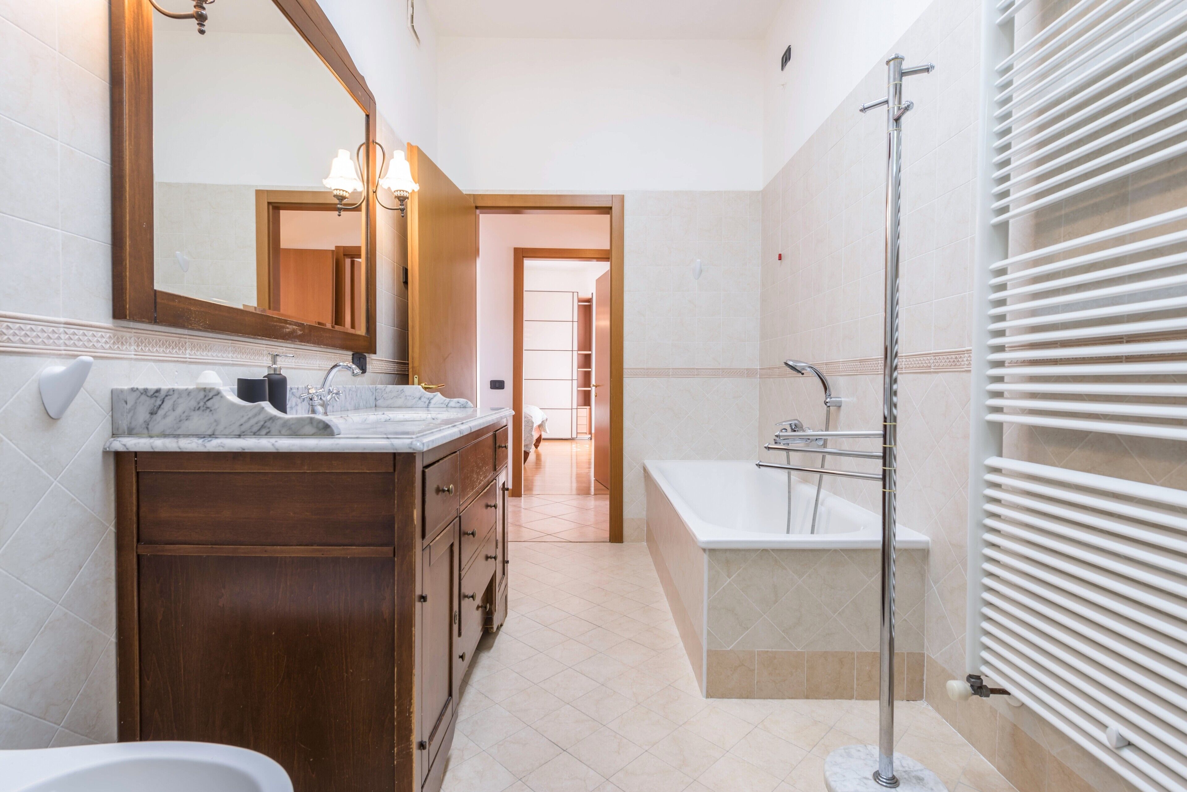 Une salle de bain moderne avec un meuble-lavabo en marbre, un grand miroir, une baignoire et une douche.