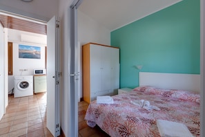 Une chambre d’hôtel comprenant un lit, une armoire, un lave-linge et un four à micro-ondes.