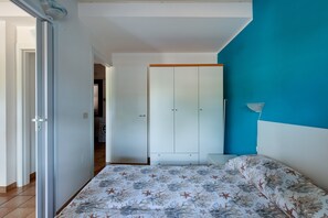 A bedroom with a bed, wardrobe, and a blue wall. - Holiday Home ‘Residenza Solemar - App 13’ with Sea View, Wi-Fi, A/C (Bosa Marina)