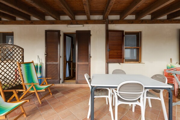 Une terrasse avec une table et des chaises, des volets en bois et une structure en treillis.