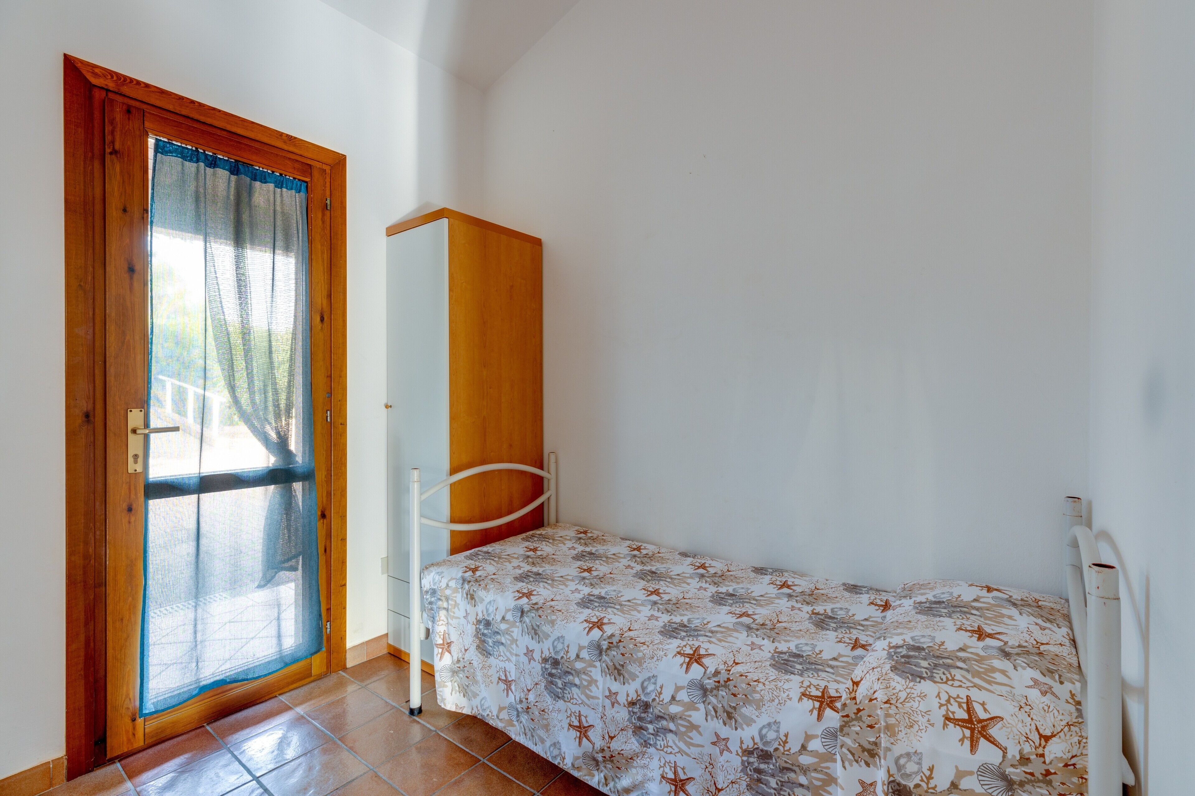 A bedroom with a bed, a wardrobe, and a door with a screen.