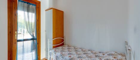 A bedroom with a bed, a wardrobe, and a door with a screen.