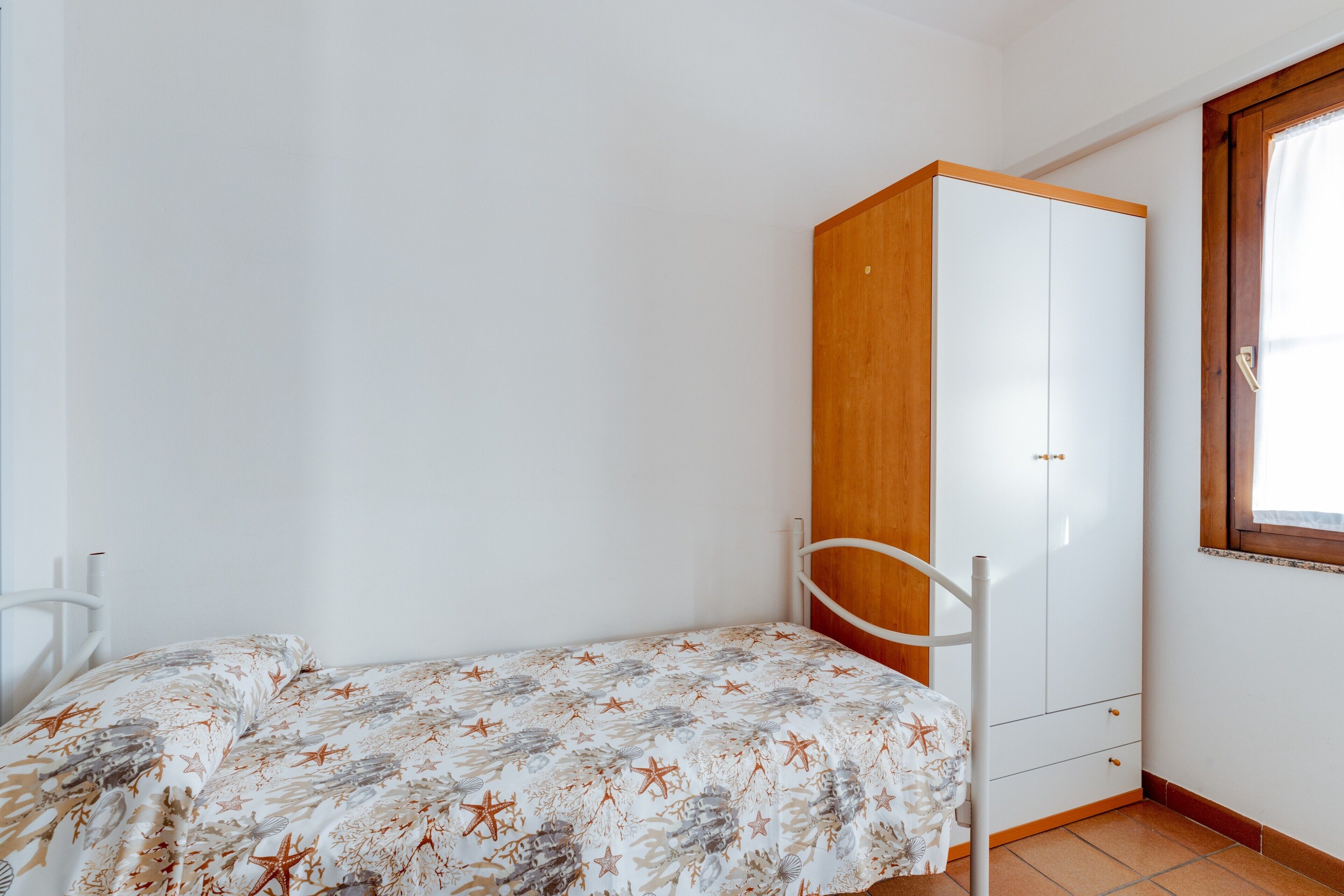 Une chambre à coucher avec un lit, une armoire et une fenêtre.