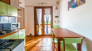 A kitchen with a microwave, cabinets, and a dining area with a table and chairs.