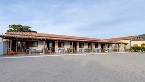 A building with a tiled roof, multiple windows, and outdoor seating with tables and chairs.