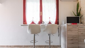 Une cuisine moderne avec deux tabourets de bar, un meuble en bois et un téléviseur.