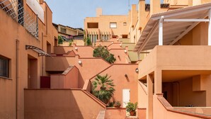 Un immeuble d’habitation doté de nombreux balcons, d’un escalier et de plantes en pot.