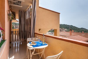 Ein Balkon mit Tisch für zwei Personen, einem Stuhl und einer Weinflasche.