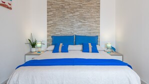 A neatly made bed with blue and white bedding, a stone-patterned headboard, and bedside lamps.