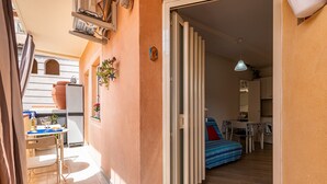 A narrow corridor leading to a bedroom with a bed and a dining area with a table and chairs.