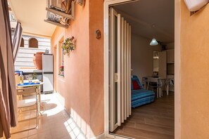 Un couloir étroit mène à une chambre à coucher équipée d’un lit et à un coin repas avec une table et des chaises.