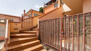 A set of outdoor stairs leading to a building entrance, a metal fence, and a clear sky.