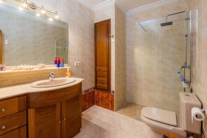 Une salle de bain équipée d’un lavabo, d’un miroir, de toilettes et d’une douche.