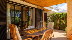 An outdoor dining area with a wooden table and chairs, a chessboard, and a potted plant. - Chalet Villa Can Jaume with Wi-Fi, A/C, Terraces & Garden; Pet-Friendly (puerto alcudia)
