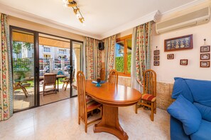 Un comedor con mesa y sillas de madera, un sofá azul y vistas al exterior.
