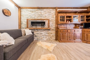 Un salon avec un mur en pierre, des meubles en bois et une cheminée.