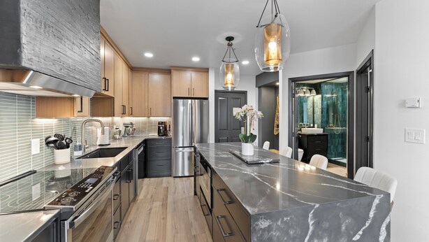 A modern kitchen with stainless steel appliances, a marble island, and pendant lighting. - Silver Mill #8162 by Summit County Mountain Retreats (Keystone)
