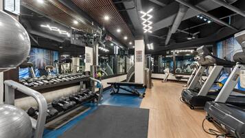 Uma academia com esteiras, halteres e bolas de exercício.