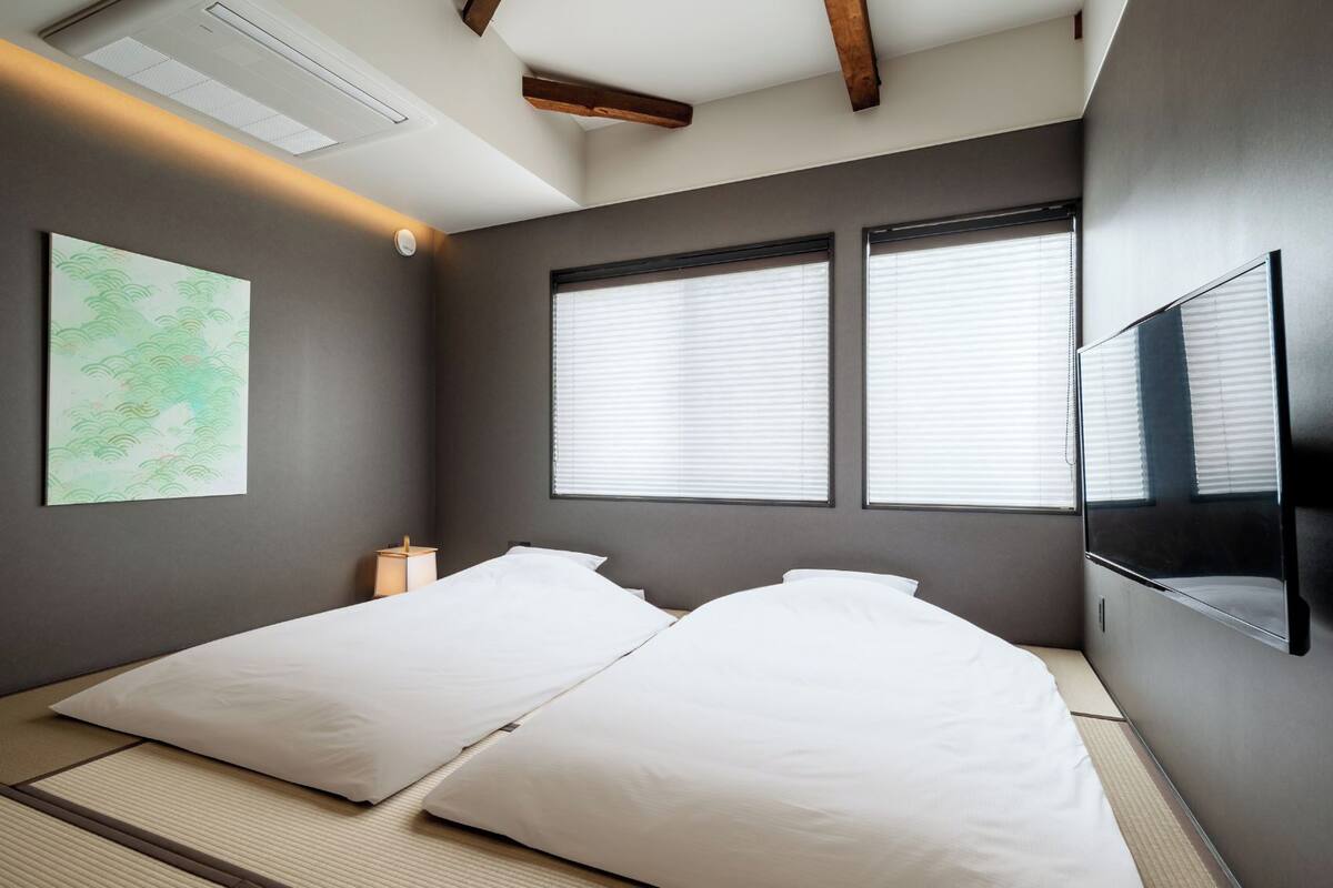 Een kamer met twee bedden, een tv aan de muur en een plafondlamp.