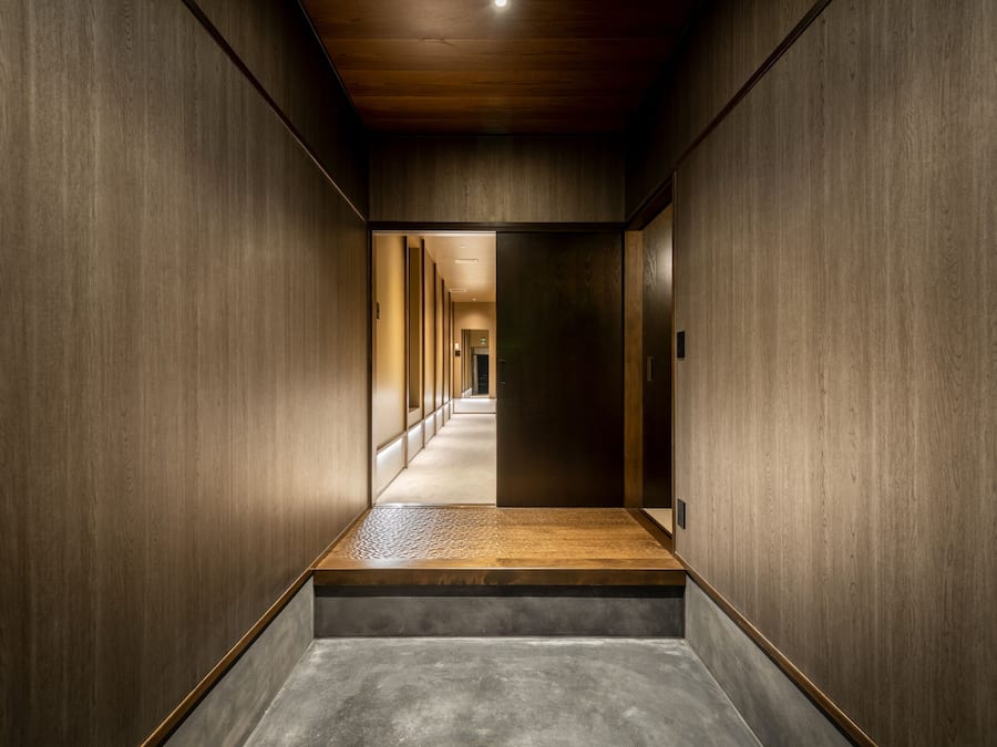 A modern hallway with wooden walls, a concrete floor, and a wooden platform at the end.