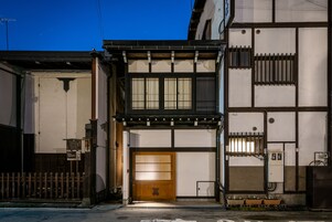 Un edificio japonés tradicional con una puerta de madera, un pequeño balcón y una valla de madera.