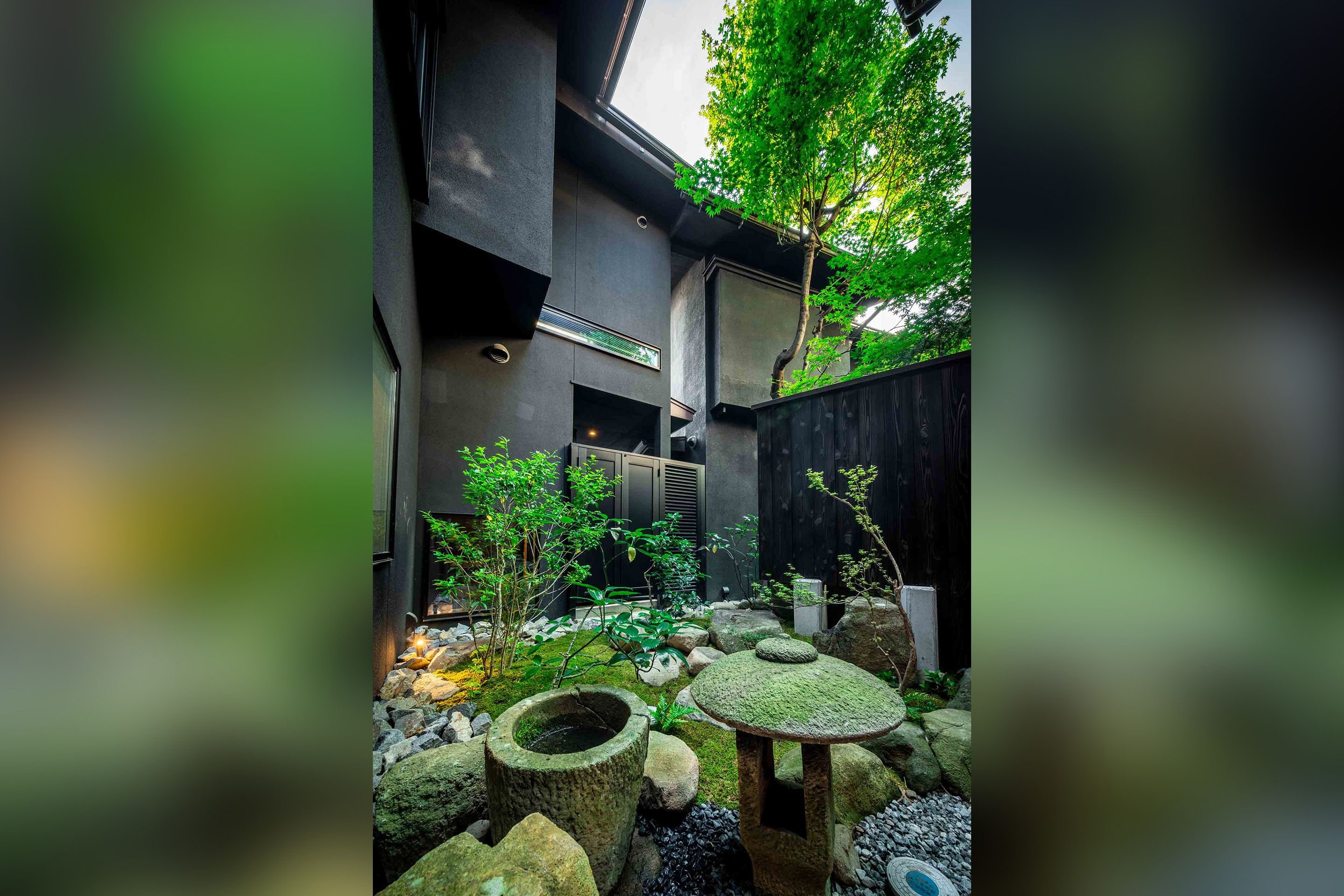 A courtyard with a stone table, rocks, and a tree.