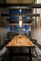 Un comedor con una mesa de madera, sillas negras y una lámpara colgante.