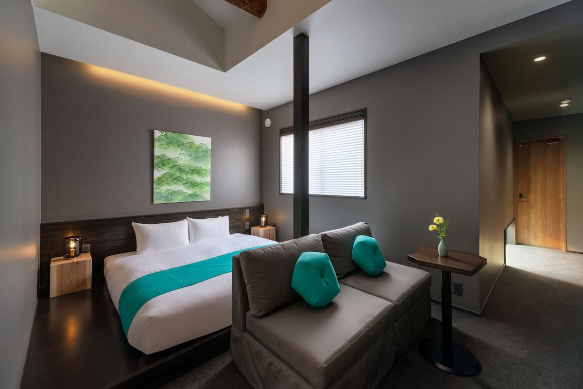 Een moderne hotelkamer met een groot bed, een bank, een kleine tafel met een bloevas en een schilderij aan de muur.