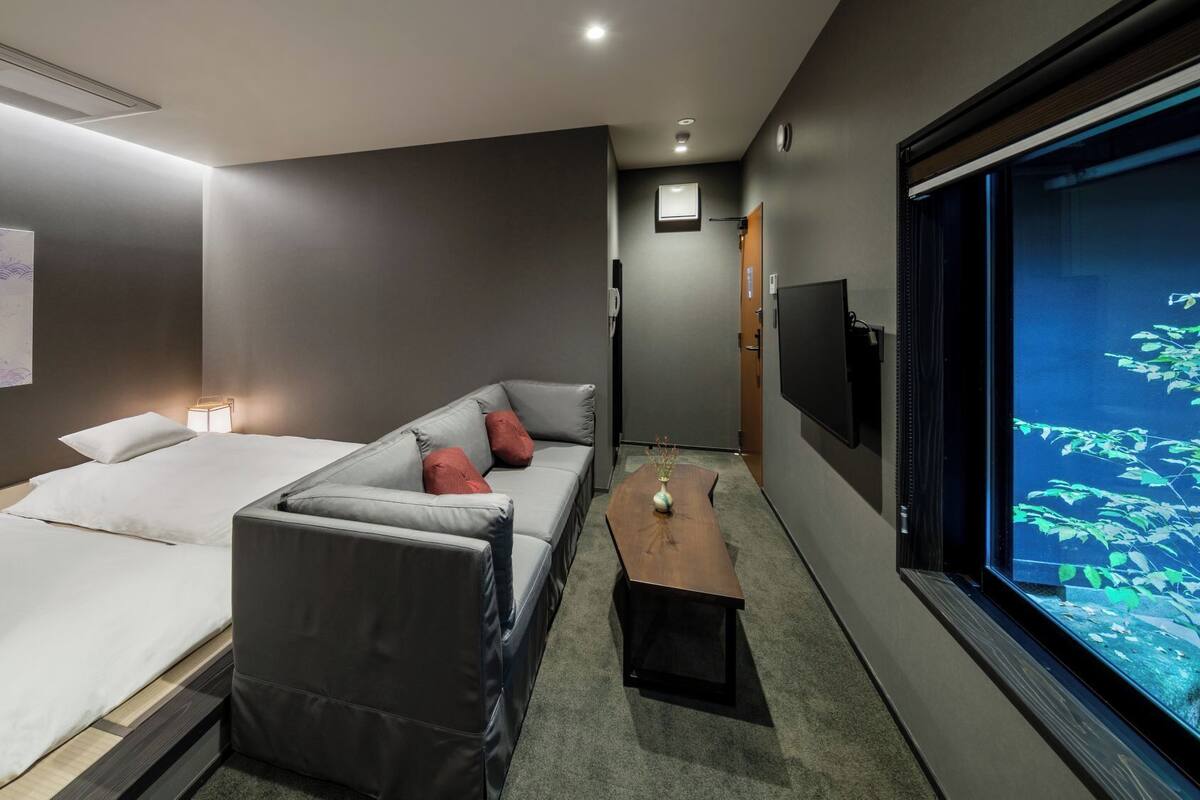 Een hotelkamer met een bed, een slaapbank, een kleine tafel en een televisiescherm.