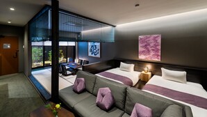 Een moderne hotelkamer met een groot bed, een zithoek, een eethoek en uitzicht op het groen.